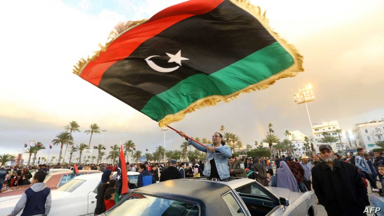 Libyans carry national flags as they gather in the capital Tripoli's Martyrs Square, to celebrate a day ahead of the eighth anniversary of the Libyan revolution, on February 16, 2019. - Eight years after the revolt in Libya against Moamer Kadhafi's authoritarian regime, a modern and democratic state remains a distant dream in a country which has been sliding from crisis to crisis. (Photo by Mahmud TURKIA / AFP)