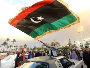 Libyans carry national flags as they gather in the capital Tripoli's Martyrs Square, to celebrate a day ahead of the eighth anniversary of the Libyan revolution, on February 16, 2019. - Eight years after the revolt in Libya against Moamer Kadhafi's authoritarian regime, a modern and democratic state remains a distant dream in a country which has been sliding from crisis to crisis. (Photo by Mahmud TURKIA / AFP)