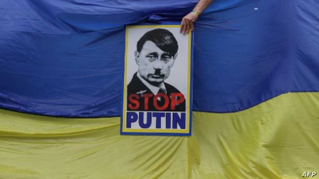 A member of South Africa's Ukrainian Association holds a poster depicting Russian President Vladimir Putin as Adolf Hitler during a protest in support of Ukraine in front of the Russian Embassy in Pretoria, on February 25, 2022. (Photo by Phill Magakoe / AFP)