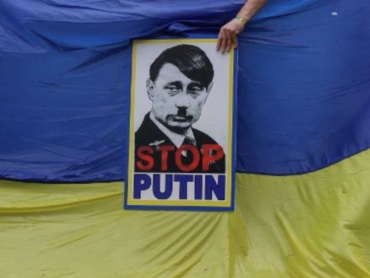 A member of South Africa's Ukrainian Association holds a poster depicting Russian President Vladimir Putin as Adolf Hitler during a protest in support of Ukraine in front of the Russian Embassy in Pretoria, on February 25, 2022. (Photo by Phill Magakoe / AFP)