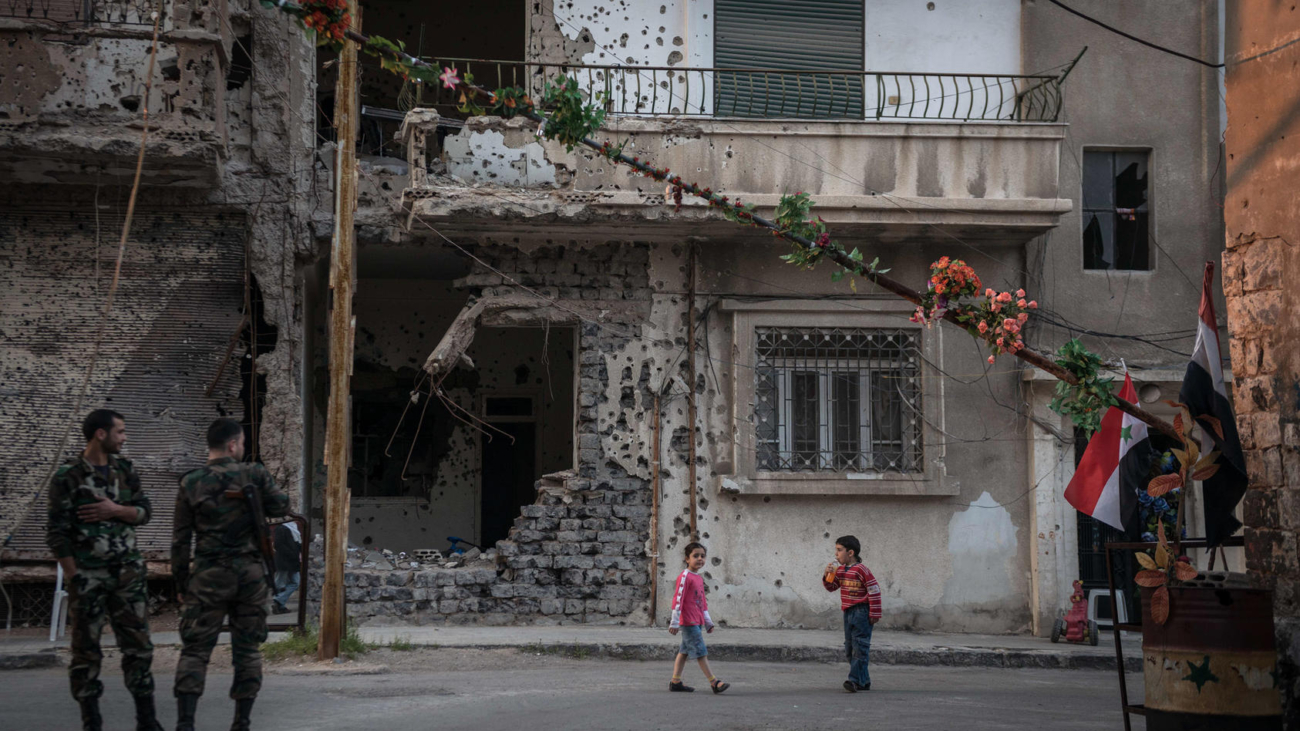 Syrian soldiers and children at a checkpoint in the besieged and devastated city of Homs, Syria, March 23, 2014. For both sides of Syria's civil war, Homs, a central Syrian crossroads with a diverse prewar population of one million, is crucial to the future. (Sergey Ponomarev/The New York Times)