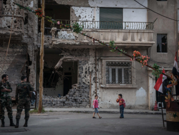 Syrian soldiers and children at a checkpoint in the besieged and devastated city of Homs, Syria, March 23, 2014. For both sides of Syria's civil war, Homs, a central Syrian crossroads with a diverse prewar population of one million, is crucial to the future. (Sergey Ponomarev/The New York Times)