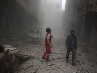 A member of the Syrian Arab Red Crescent looks for survivors in a street covered with dust following air strikes in the rebel-held town of Douma, on the eastern edges of the Syrian capital Damascus, on December 13, 2015. The Syrian Observatory for Human Rights said rockets fired by regime forces rained down on Douma, one of the largest towns in the opposition-held Eastern Ghouta region. AFP PHOTO / ABD DOUMANY (Photo by ABD DOUMANY / AFP)